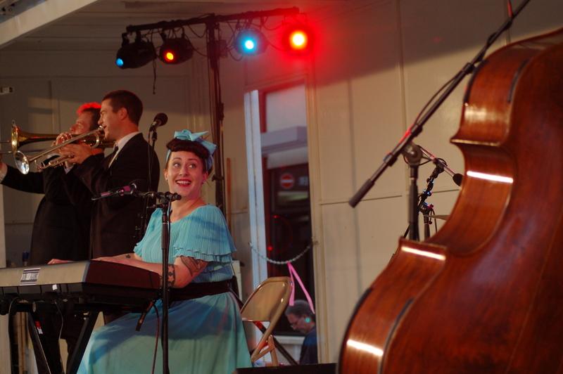 Davina Sower of Davina and the Vagabonds looks back at upright bassist Michael Carvale. In the foreground Dan Eikmeier, trumpet and Ben Link, trombone provide a jazzy overtone for Sowers vocals.
