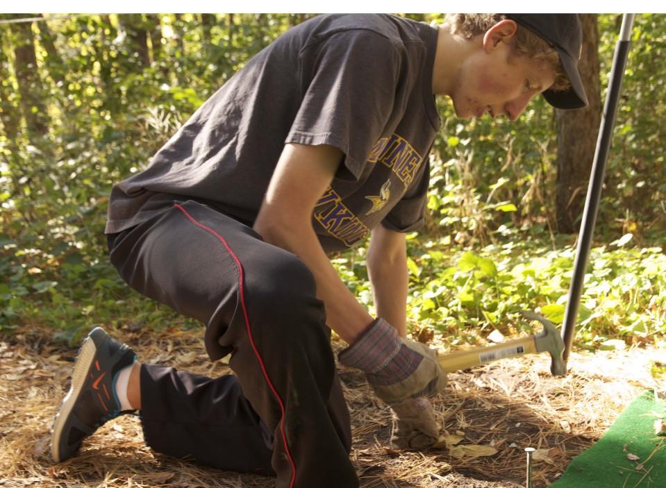 Senior and NHS member Sam Anderson hammers a nail into the ground in preparation for the Westwood Nature Centers Halloween festivities. 