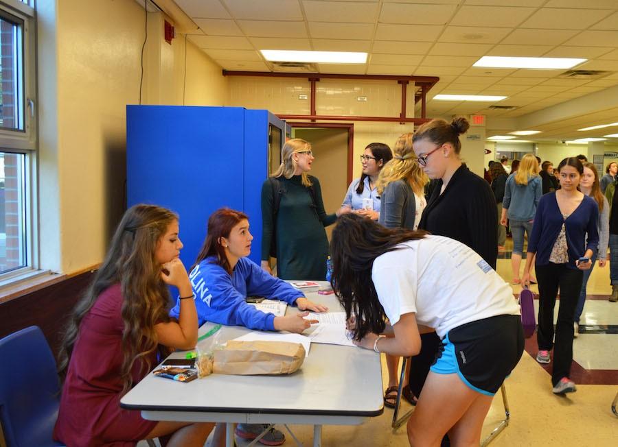 Seniors Brigid Duffy and Elena Basil hand out blood drive sheets to interested students.