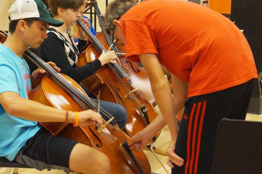 Senior Aedan Foner helps tune junior Benjamin s cello during class Sept. 
