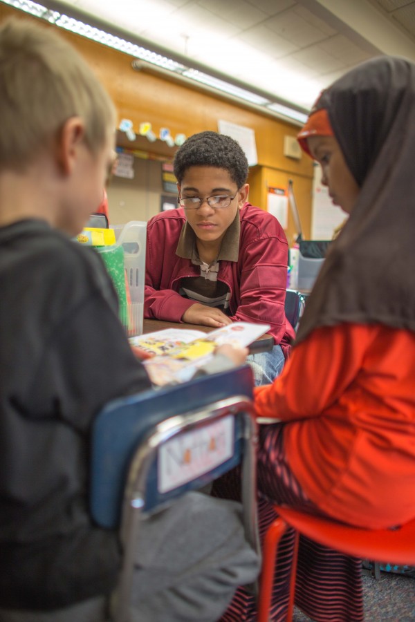 Second graders Henry Weig (left) and Rauda Sheik (right) read a story to freshman volunteer Sean Davenport, center, Nov. 20 at Aquila Elementary School. Davenport said it was exciting to see how much the younger kids knew.