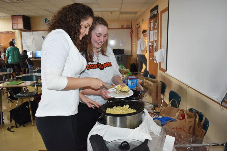 Seniors Selina Hampton and India Rounds dish out food during the Echowan party Oct. 29 to celebrate finishing the first package of the yearbook. 