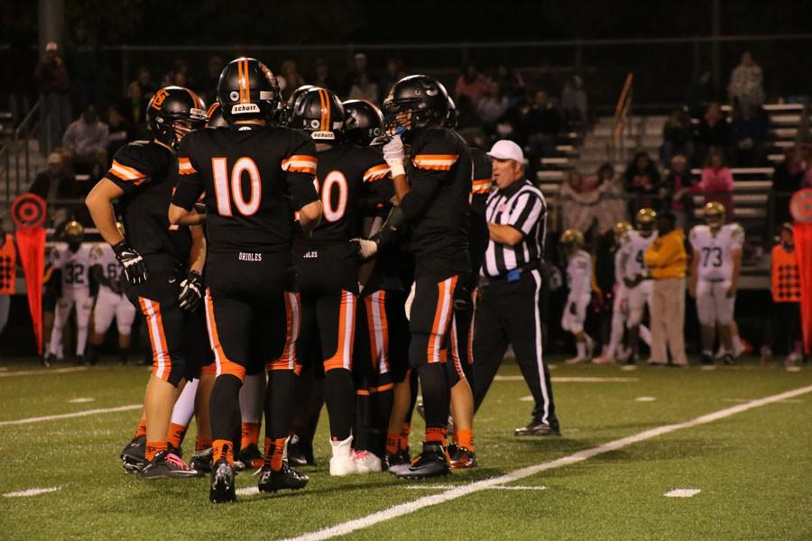 Varsity+football+team+huddles+together+to+decide+the+next+play+at+the+homecoming+football+game.
