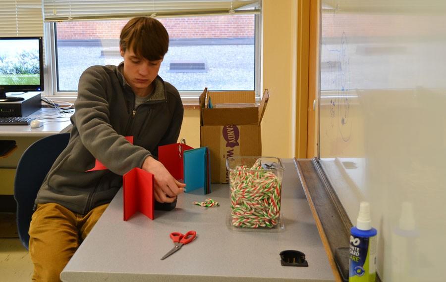 Sophomore Everett Deiman places candy canes inside holiday cards students can purchase. 