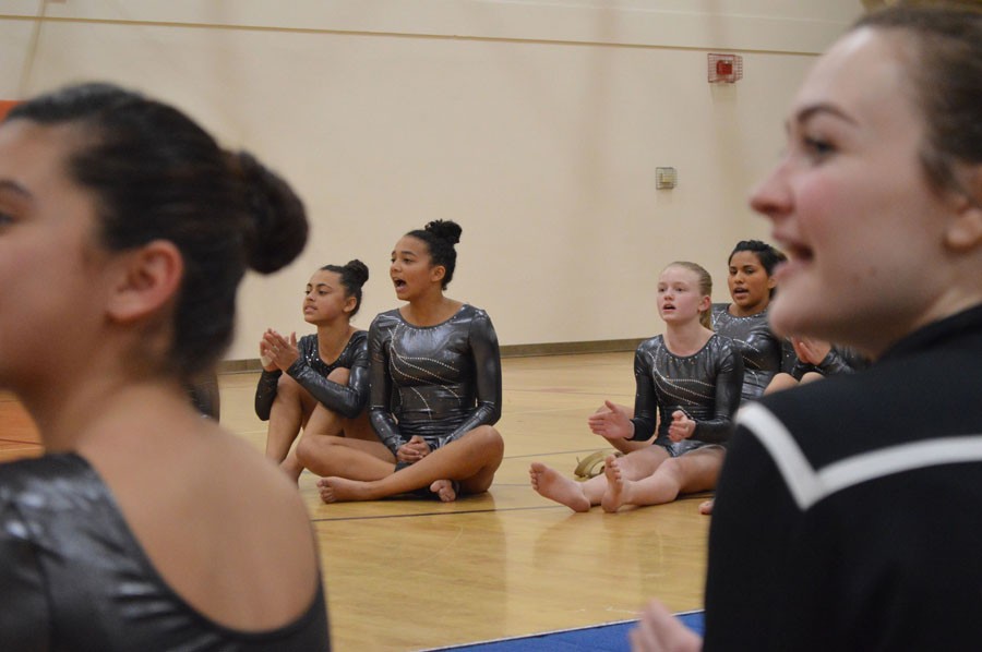 Gymnasts cheer for their teammates as they compete during the teams first gymnastics meet Dec. 1. 