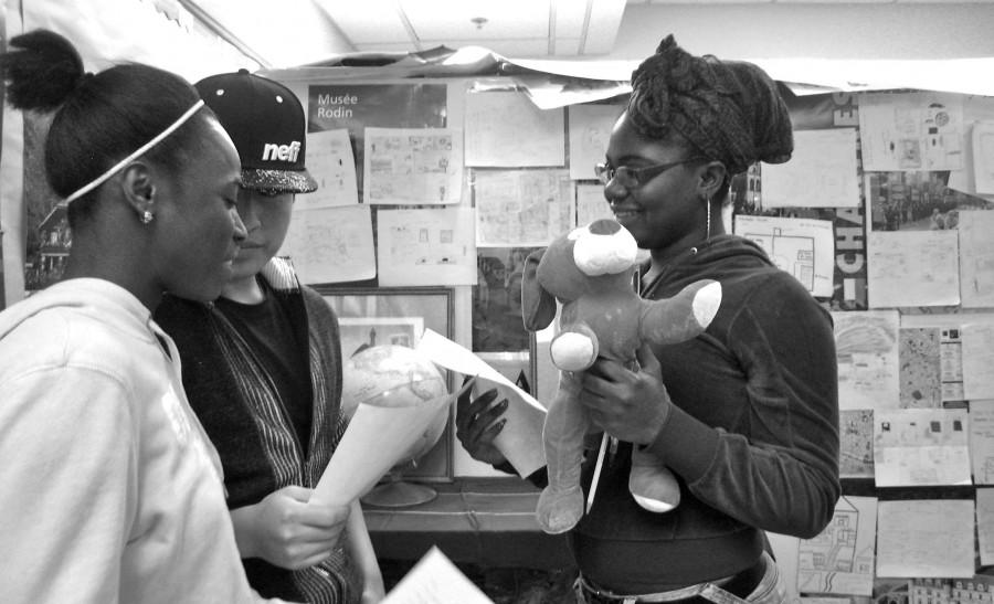 Junior Estelle Djaoupe uses a prop to participate in a skit between French 1 and French 4 with sophomores Melissa Bakayoko and Wilson Tamay Pineda during fourth hour Dec. 15. 