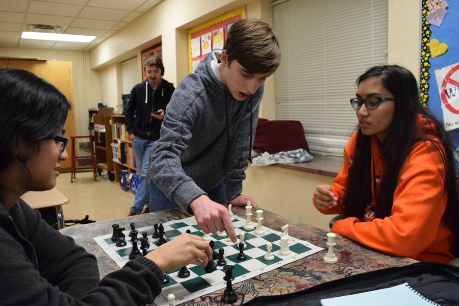 Playing since second grade, junior Eric Manuel shares his knowledge with new Chess Club members on Jan. 20. Manuel guides juniors Tehya Latchman and Dyana Dominguez Chon through the game of chess. According to Manuel, the importance of chess lies in its ability to increase productivity and time management.