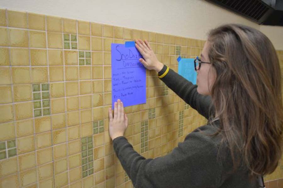 Senior class president Jessica Schmidt hangs up posters Feb. 5 around the school to give information about SnoDaze week. The week will feature 3x3 basketball, dodgeball, Battle of the Bands and volleyball.