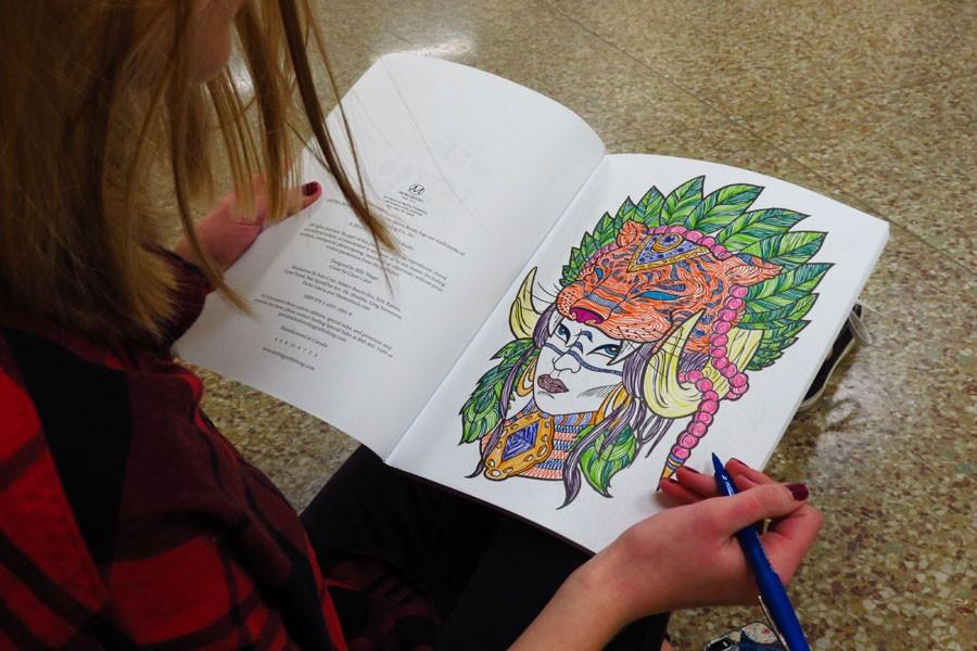 Junior Megan Wojtasiak adds the finishing touches to her artwork in her coloring book.