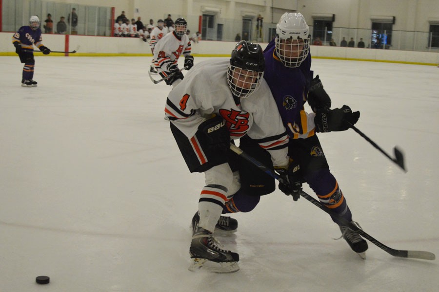 Sophomore Jonny Sorenson uses his body to block rival in the boys hockey game Jan. 30.