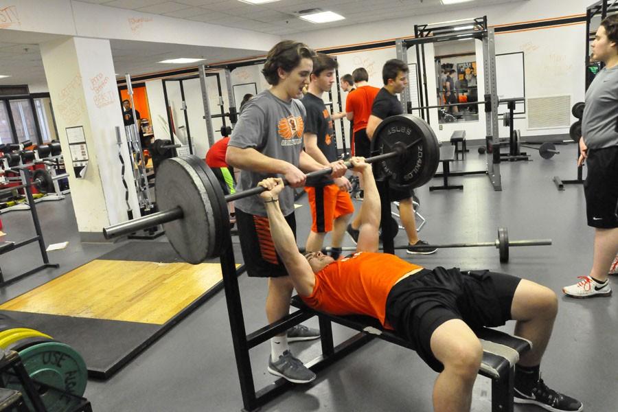 Junior Zollie Kaplan bench presses at Strength and Conditioning while Junior Logan Romero spots him.