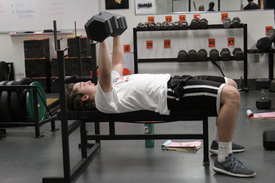 Junior Logan Romero bench presses during strength and conditioning practice.