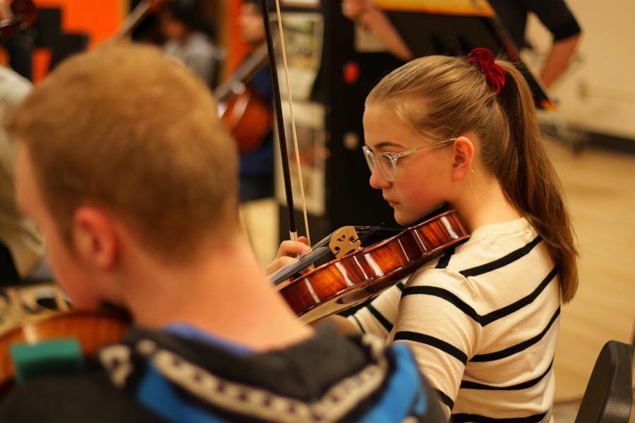Freshman Abby Intveld plays in orchestra during a rehearsal during class. The orchestra travels to New York May 27.