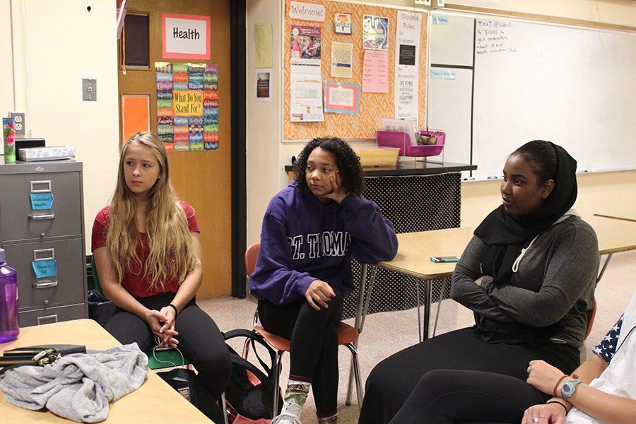 Sophomores Emily Kirchner and Nyah Johnson and senior _____ listen to junior Ellery Deschamps talk to the group about the Cocks v. Glocks controversy in Texas at the SHEC meeting Oct. 6.