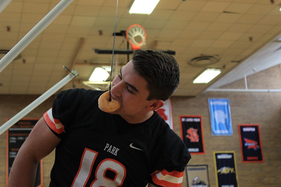 Senior football captain Zollie Kaplan takes a bite out of a doughnut at Fridays pep fest. The object of the game is to eat the doughnut without using ones hands. 