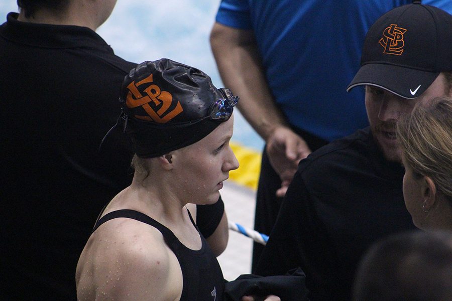 Kailey Delozier talks to coach Joe Yaeger and assistant coach Amanda Forsberg following her 50-yard freestyle event. Kailey placed 10th and qualified for finals where she placed 10th as well.
