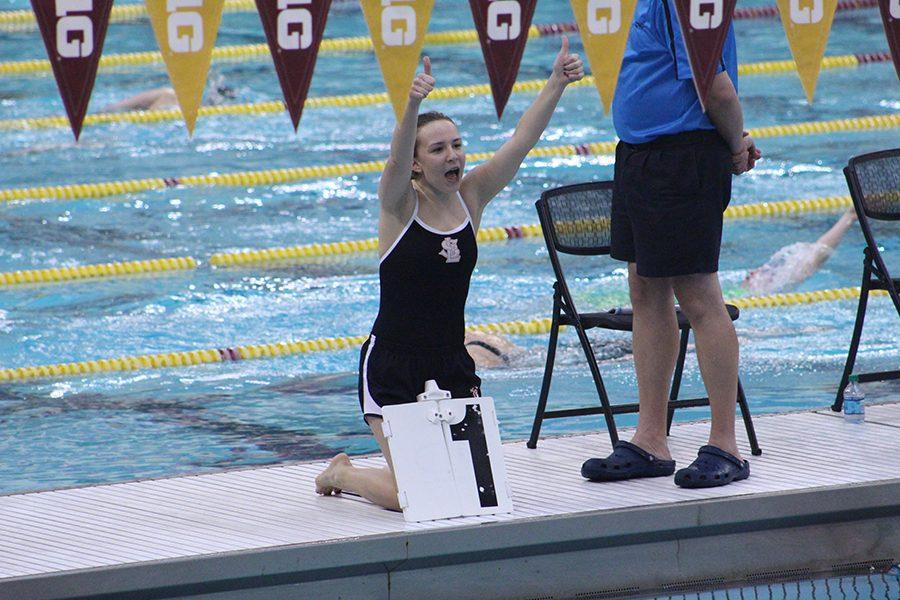 Senior Katie Orton cheers her eighth grade sister Elizabeth Orton on when her name is called for the girls 500-yard freestyle event. Katie counts laps during the event.