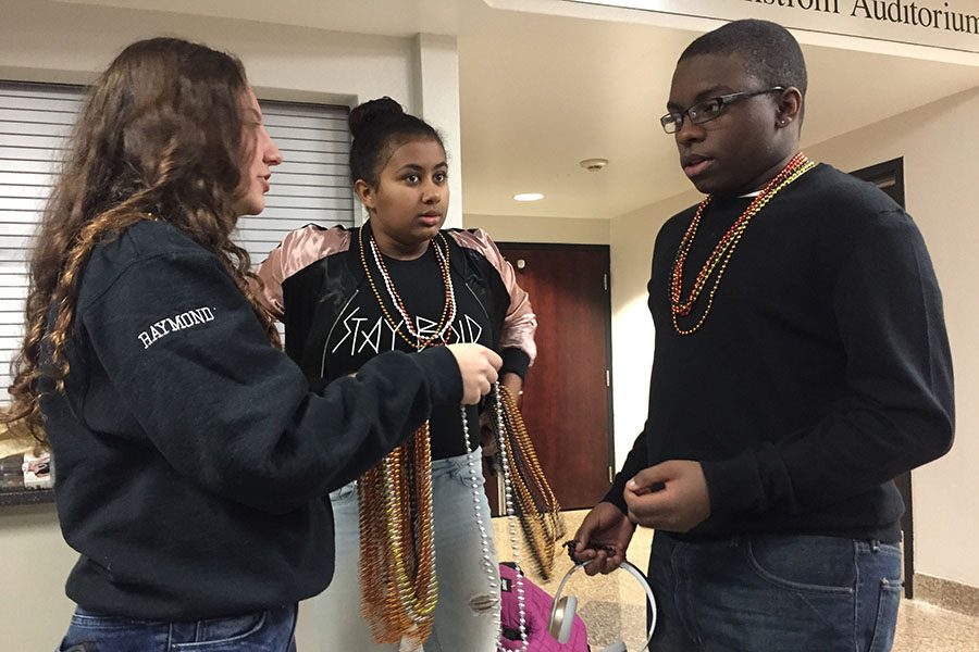 Sophomores Leila Raymond and Sidney Hosfield give beads to junior Jeffery Robinson while explaining the councils Take Pride Week.