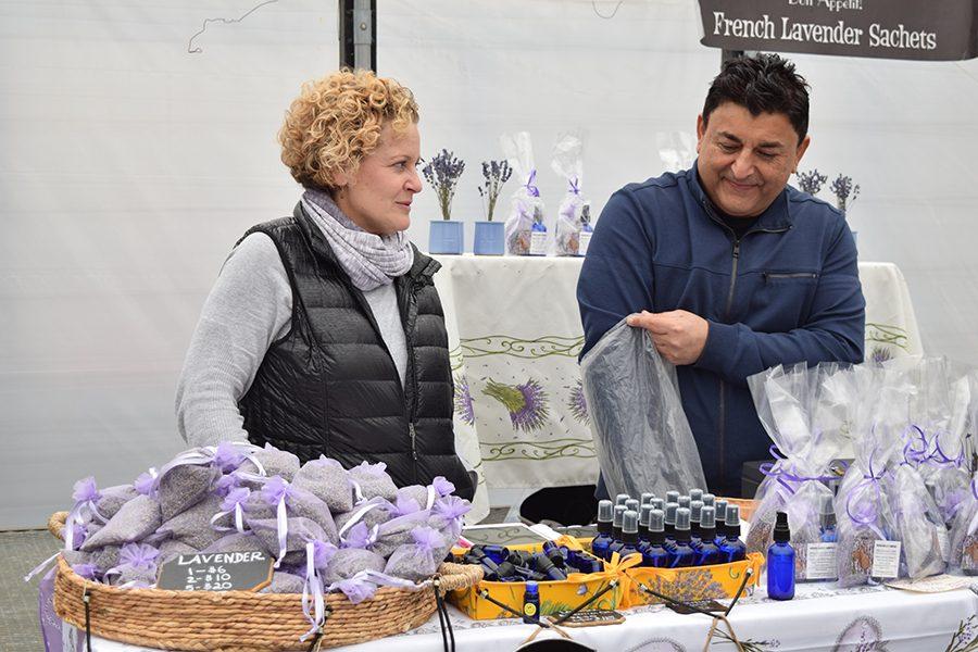 Laurie Golchin and her partner, who works for a business called French Nugget, restock their stand.  They sell products such as lavender sachets, essential oil and sprays.