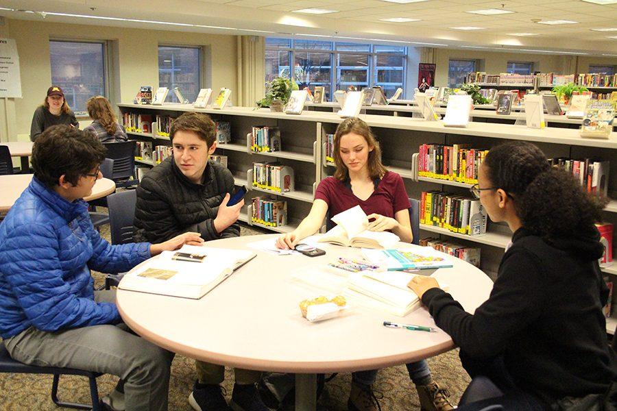 Sophomores Ethan Kahn and Chloe Blodgett discuss their English book assignment Neither Wolf Nor Dog with friends before school in the media center.
