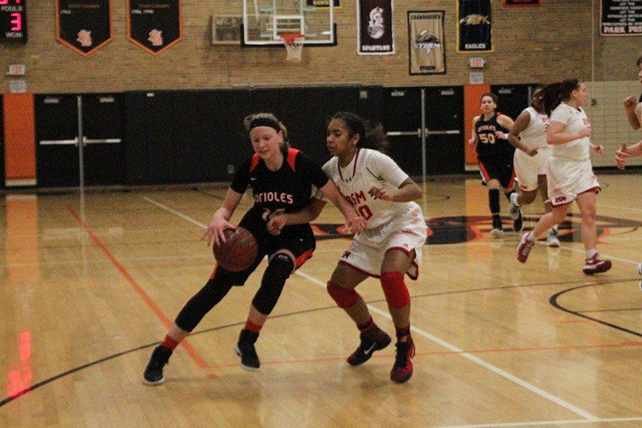 Sophomore Lindsey Olson dribbles past a Benilde defender. The Orioles beat the Red Knights 63-46.