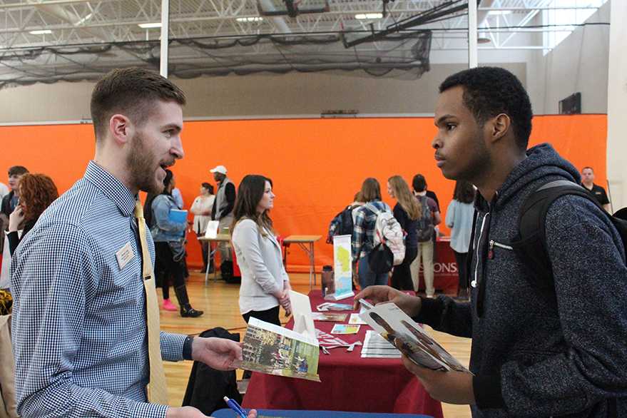 Junior Mahamed Mahamed talks to a college representative from the  University of Wisconsin–Eau Claire. There was a large representation of schools at the college fair March 15. 