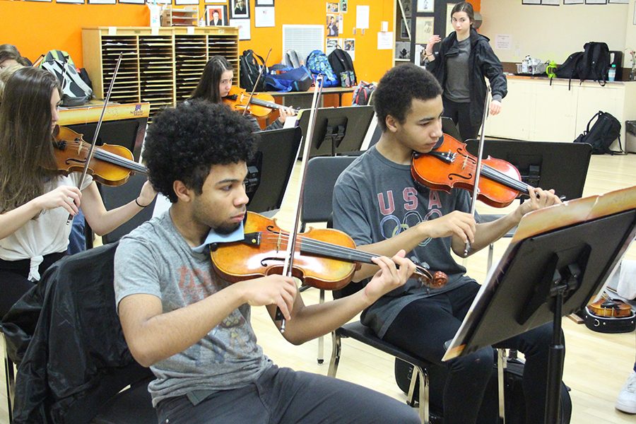 Justin Wilson and David Benjamin rehearse a piece with their orchestra class. The Tour of Schools is April 28.