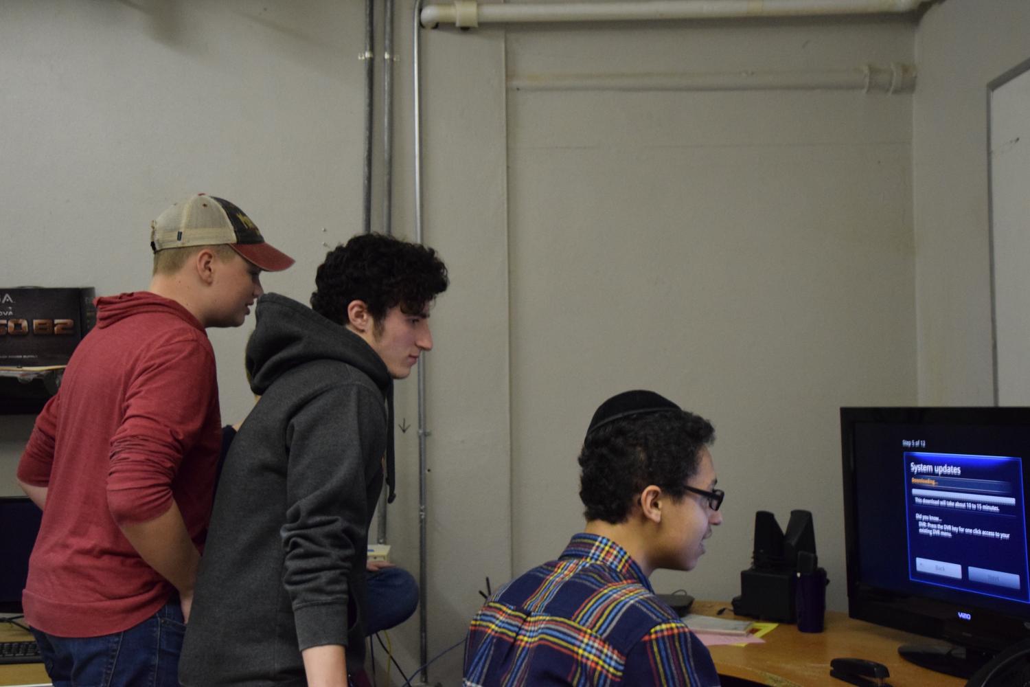Senior Simon Lewin, junior Mordechai Leahy and sophomore Will Erdmann gather around a computer while playing a game at a Park Tech meeting April 26.