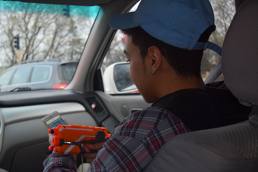 Junior Justin Lamar waits with his Nerf gun in an effort to kill another player in the Nerf assassins game. 