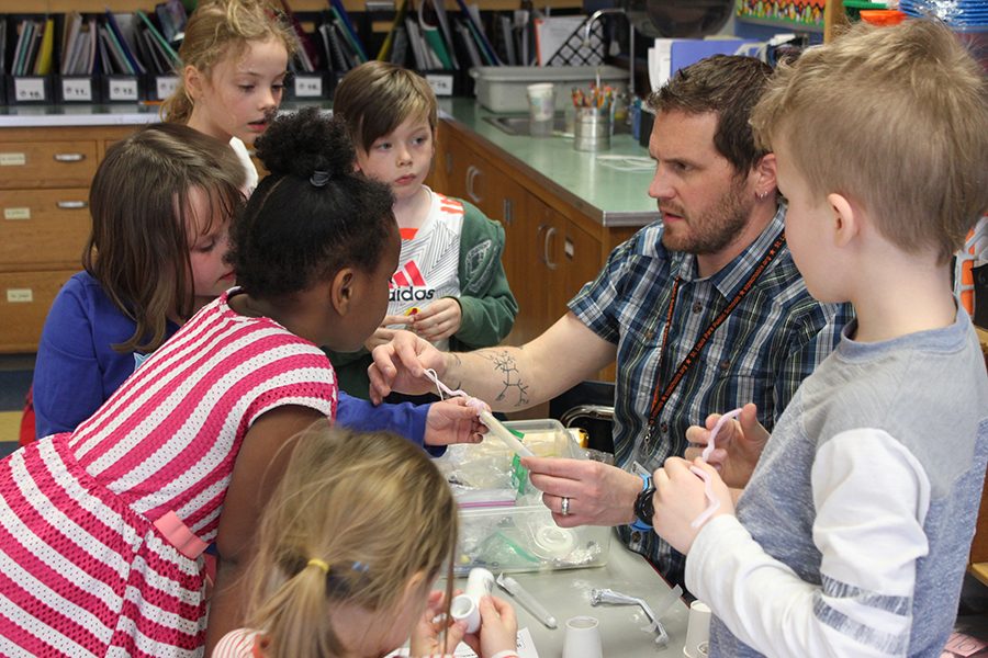 High school science teacher Patrick Hartman demonstrates to Park Spanish Immersion first graders how to build Hand Pollinators, a project that simulates what pollinators do to plants. April 13.