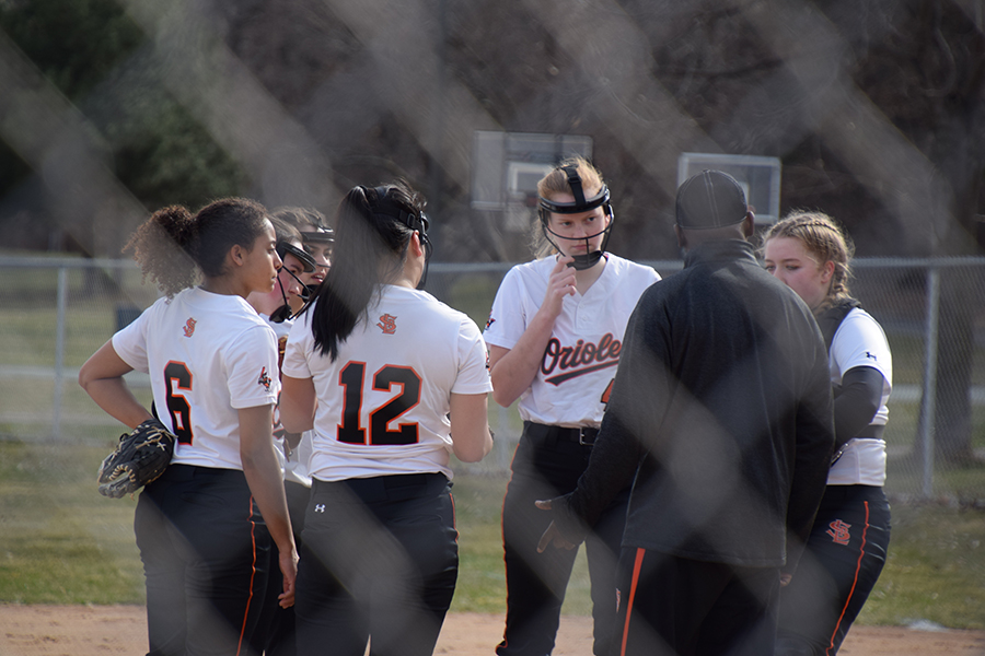 Park softball players meet in the infield during a game against Robinsdale Cooper at Aquila Park. Junior softball player Savannah Romero said establishing a home field will give the athletes more confidence. 