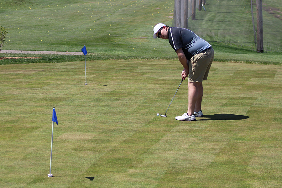 Senior Zach Hatcher sets up for a putt on the practice green. Boys golf captain Billy Nicholls said the team needs work on their putts during matches. 