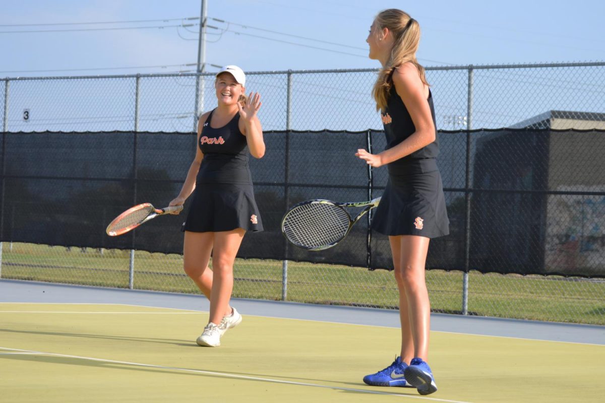 Senior Lillie Albright and sophomore Kenna Jacobson share a laugh during their match against Cooper Sept. 19. The orioles defeated the Hawks 7-0. 