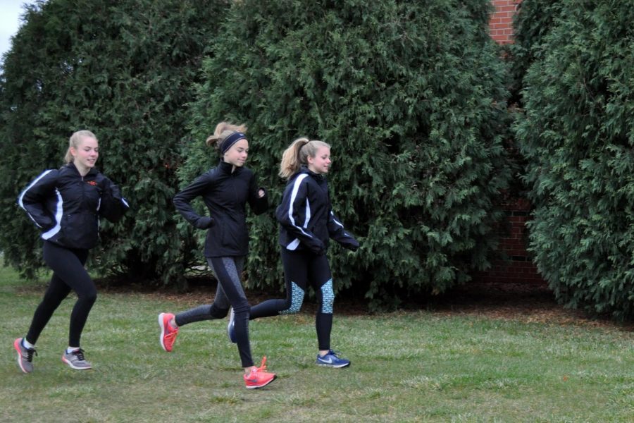 Sophomores Carissa Prestholdt and Kaia Myers run alongside fellow teammate eighth-grader Josie Mosby to help her train for the state meet Nov. 4.
