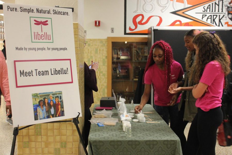 Libellu interns senior Makagbe Kuyateh and junior Rachel Young showcase the brands skincare products to passing students in the B1 hallway Dec. 5.