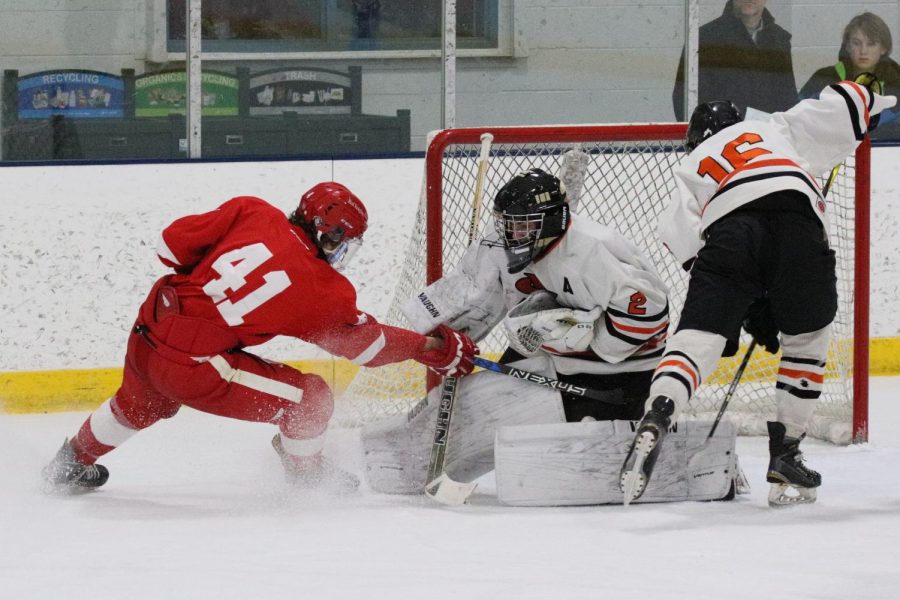 Senior assistant captain Atticus Raasch blocks a shot from Benildes Jerome Newhouse during the first period of the game on Feb. 13. Despite the loss, Raasch made 39 saves throughout the game.