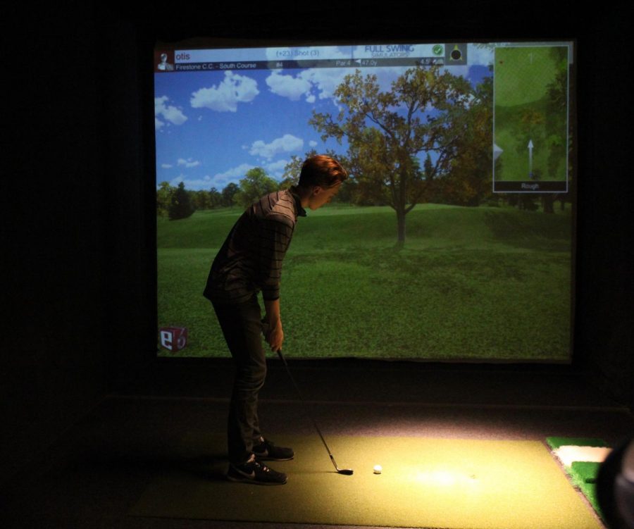 Senior Otis Walvatne prepares to hit an approach shot on a golf simulator at Lifetime Fitness in St. Louis Park. Practice was held at the indoor location as a result of the snowfall. The golf teams first match will take place at 3 p.m. on May 1 at  the Minneapolis Golf Club against the Academy of Holy Angels