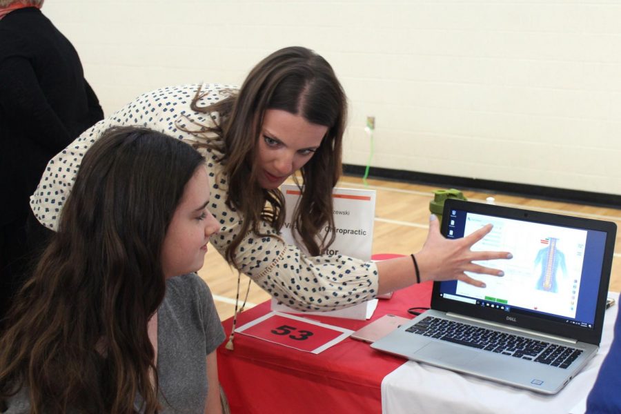 Freshmen Talia Lissauer learns from chiropractic representative about her job during the career expo April 25.  