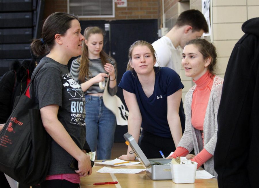 Science teacher Jenny Madgal registers and pays seniors Megan Perkins and Hanna Schechter, who organized the H2O Dodgeball Tournament fundraiser, at the start of the tournament April 18.