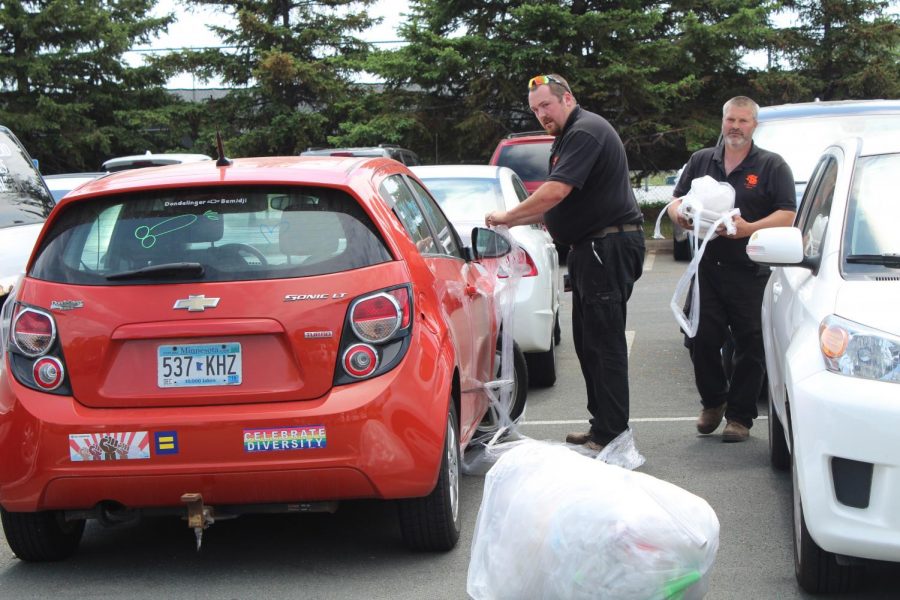 Members of the janitorial staff clean up plastic wrap from cars after a Senior prank on May 24.