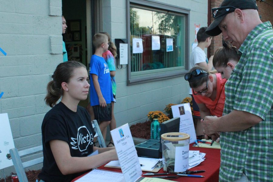 Senior and SLP Nest board member Lexi Lee sells raffle tickets to a community member at the SLP Nest street party Aug. 15. All money and donations collected at the event will be used support and run the SLP Nest.
