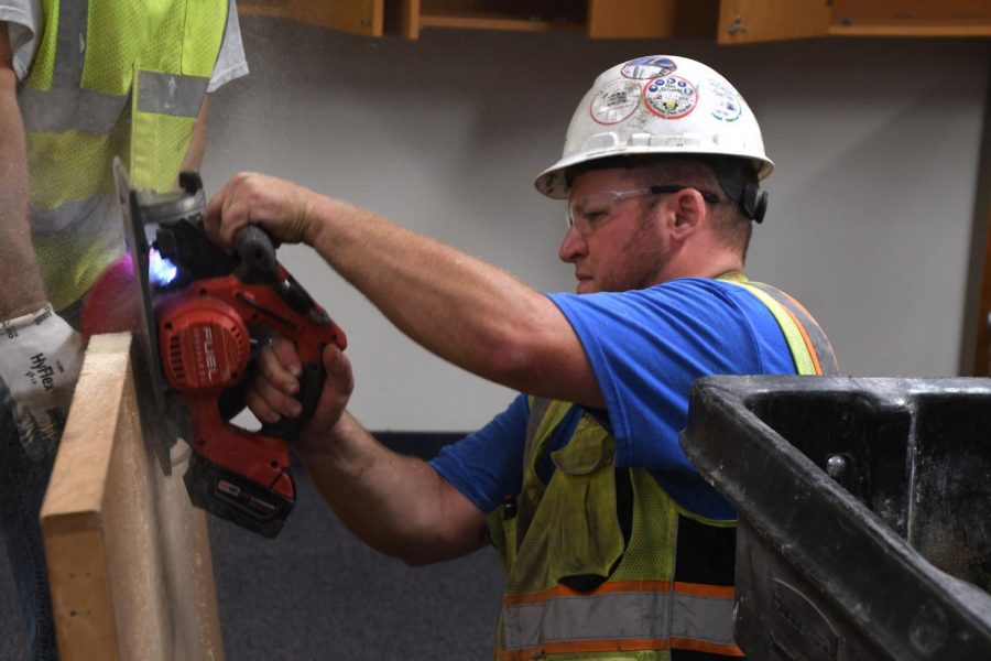 A construction worker uses a saw to take a handle off a door at the high school Aug. 20. District improvements will be completed by 2022, according to District facilities manager Tom Bravo.