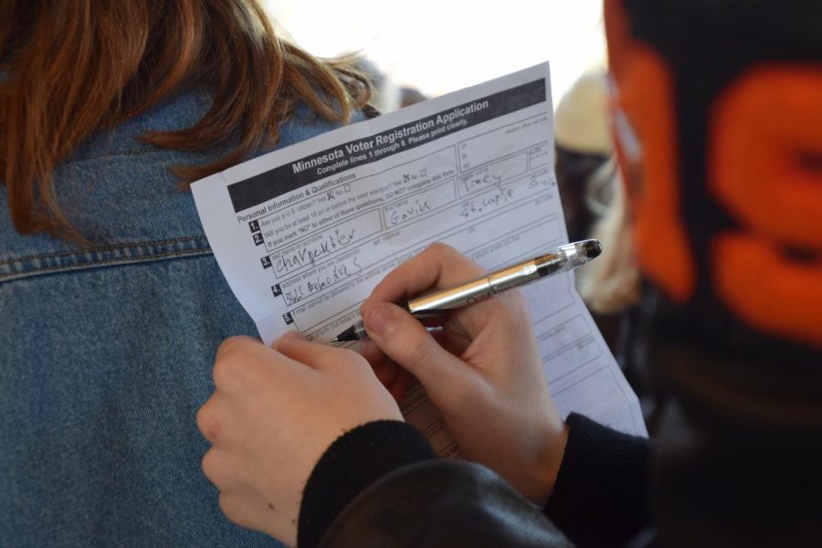 Senior Gavin Carpentier signs a voter registration application during the national high school walkout last year on March 14. ACT SLP is leading a voter registration assembly Sept. 26 to encourage eligible seniors to register to vote for the elections in November.  
