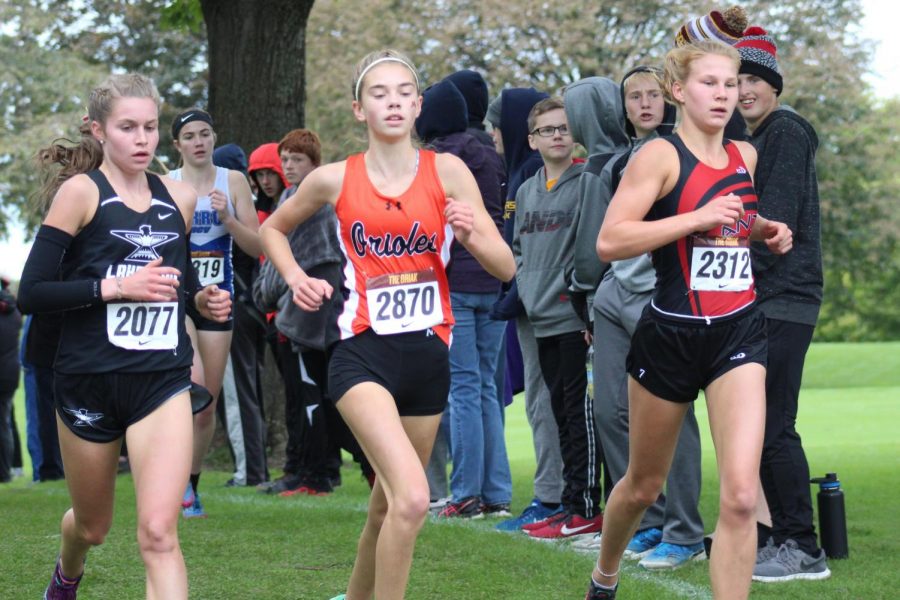 Freshman Josie Mosby runs with two competitors in the Griak race, Sept. 29. Mosby placed first individually and the team placed first overall.