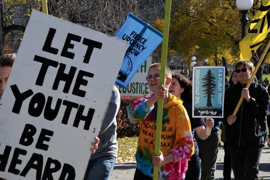 Loud and proud: Junior Maddie Lind marches alongside juniors Zoe Younger and Isaac Wahl while holding a sign that reads We Rise. Lind marched Oct. 28 at the Minnesota State Captiol to advocate for a Fossil Free Future. All three are members of Roots and Shoots.