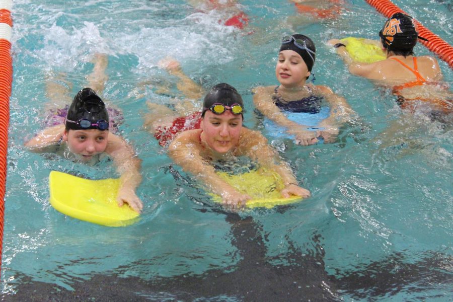 Eighth graders Quinn Hartnett, Caroline Forester and Stephanie Stone warm up in the swimming pool on kickboards during practice Oct. 22. Earlier this year the swimming pool wasnt its usual temperature.