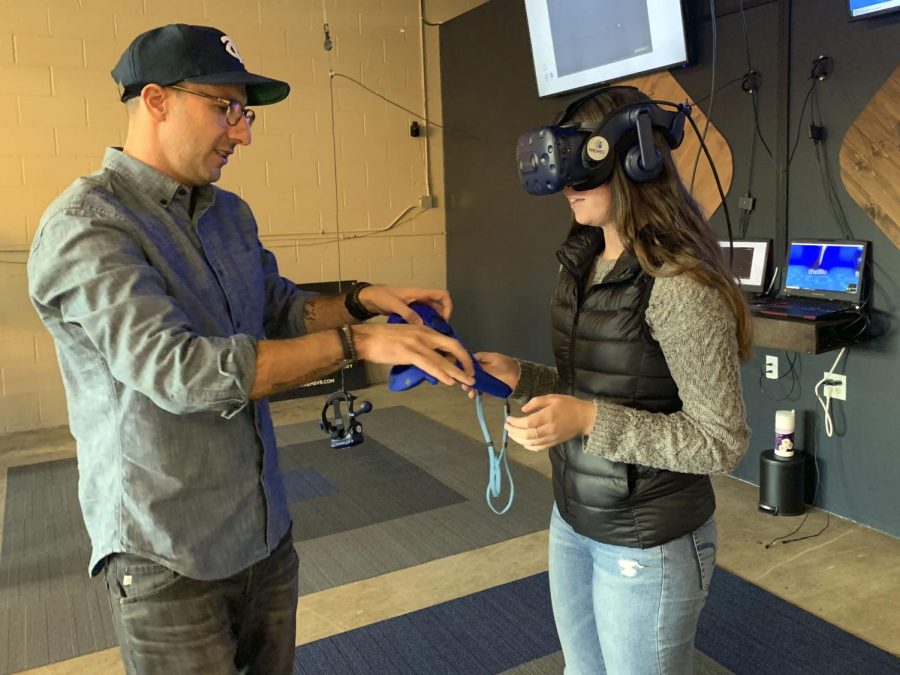 Owner of Rem5VR lab, Amir Berenjian helps set up a game of virtual reality fruit ninja.