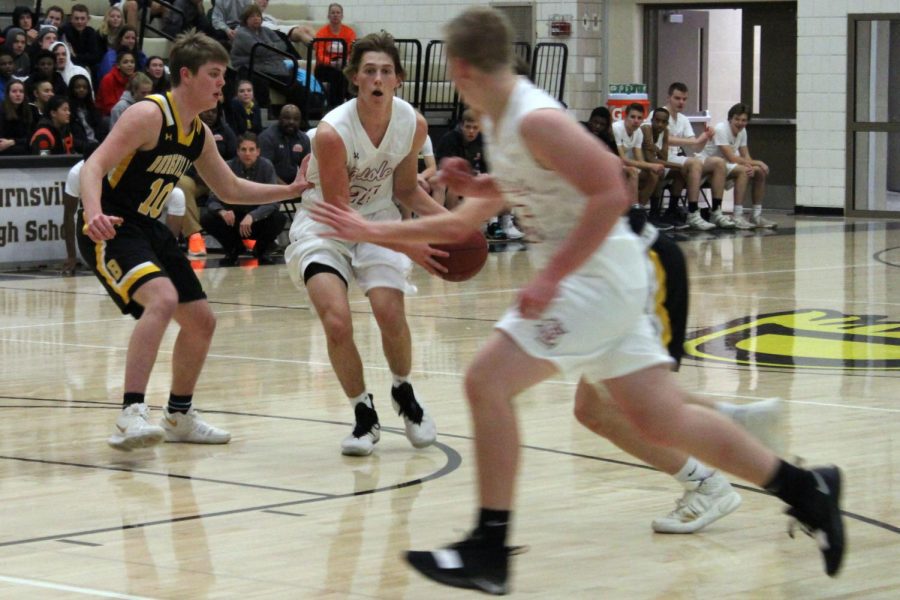 Senior Anthony Odens pushes through two opposing players in attempt to pass ball to senior Jacob Houts. Parks first game of the season took place against Burnsville Nov. 30.