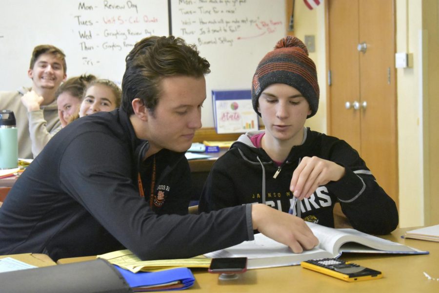 Bobby Otto helps sophomore Elliot Salmon with his math homework. According to Otto, he tries to incorporate the mindfulness aspect of yoga into the classroom because it benefits himself and his students.