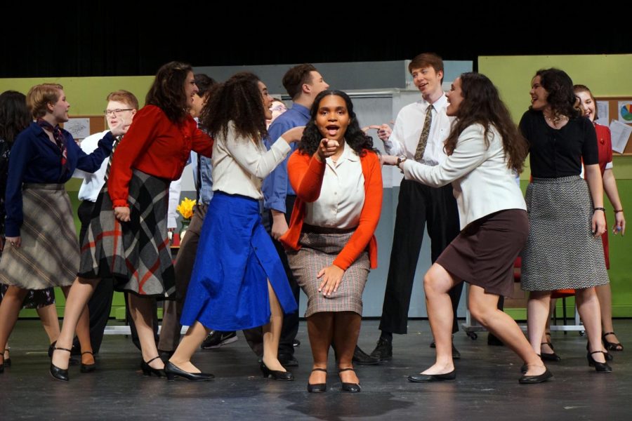 Senior Ayanna Nathan sings center stage with other cast members in the opening number of “9 to 5 the Musical”.